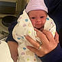 baby, newborn, infant, swaddle_blanket, striped_hat, hospital, hospital_room, medical_equipment, polka_dot_pattern, hand, engagement_ring, person_holding, stool, portrait, smile, eyes_open, cozy, blanket, adult_hand, floor