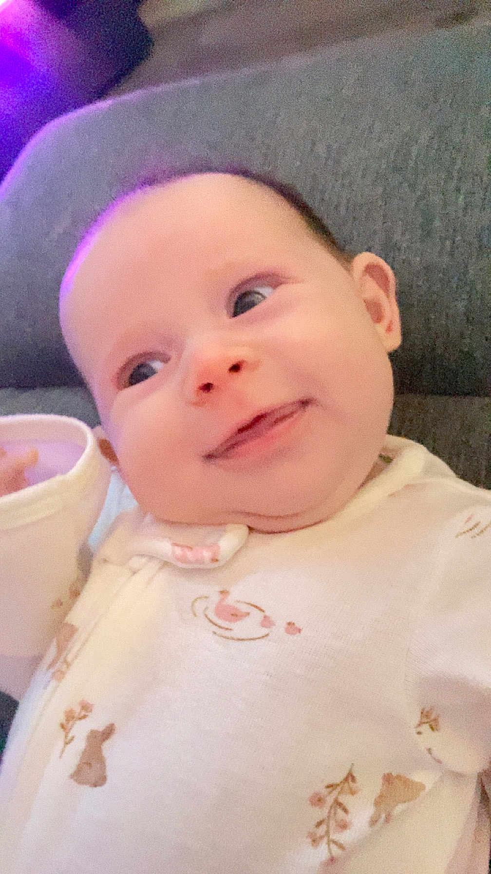 Oakley is registered to the contest to win money with this photo: baby, infant, smile, onesie, sofa, couch, face, cheeks, eyes, ear, hand, cup, closeup, portrait, indoor, cozy, soft_lighting, happy, adorable, newborn