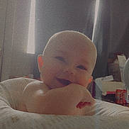 Carson joined the competition — help win amazing prizes! baby, infant, child, smile, smiling, bald, head, face, eyes, hand, arm, baby_seat, seat, blanket, pillow, curtain, window, indoor, room, cozy