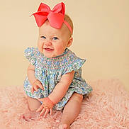 Millie Kate is registered to the contest to win money with this photo: baby, child, smiling, bow, headband, dress, floral, pink_rug, sitting, cute, happy, portrait, infant, skin, hand, feet, indoors, soft_texture, playful, blue_eyes