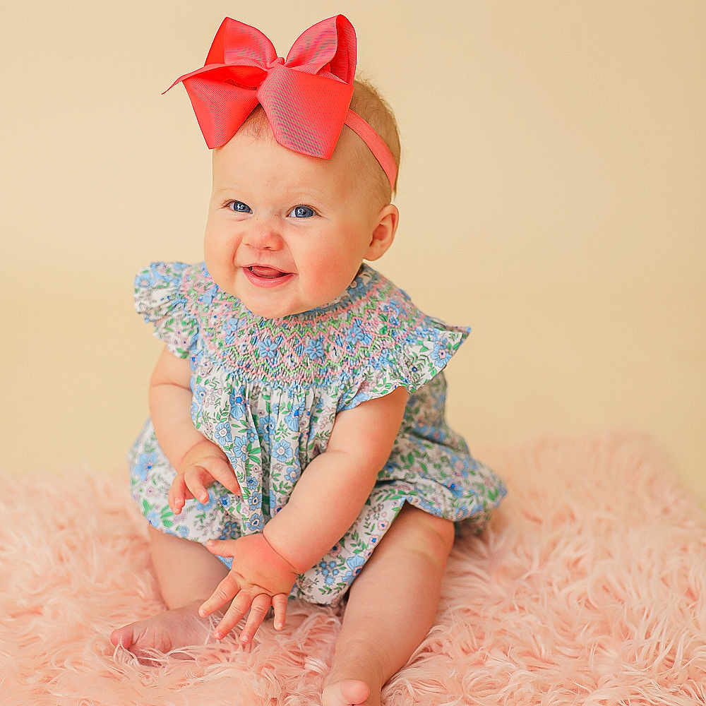 Millie Kate is registered to the contest to win money with this photo: baby, blue_eyes, bow, child, cute, dress, feet, floral, hand, happy, headband, indoors, infant, pink_rug, playful, portrait, sitting, skin, smiling, soft_texture