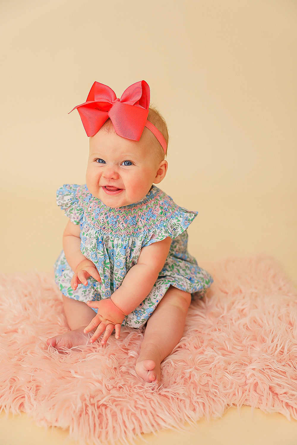 Millie Kate is registered to the contest to win money with this photo: baby, child, smiling, bow, headband, dress, floral, pink_rug, sitting, cute, happy, portrait, infant, skin, hand, feet, indoors, soft_texture, playful, blue_eyes