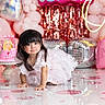 Halle is registered to the contest to win money with this photo: toddler, child, birthday_party, dress, crawling, balloons, pink, cake, heart_shaped_balloon, confetti, celebration, party, decorations, frilly_dress, girl, indoor, floor, smiling, cute, photography