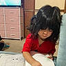 child, coloring, book, red_shirt, black_hair, couch, drawing, indoor, furniture, television, pink_drawers, carpet, person, young_child, art, concentration, home, living_room, casual, seated