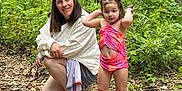 Cora joined the competition — help win amazing prizes! adventure, child, crouching, family, forest, greenery, happy, nature, outdoor, person, pink_shoes, plants, playful, riverbank, rocks, smile, summer, swimsuit, water, woman