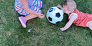 Luca is registered to the contest to win money with this photo: activity, baby, casual, child, children, daylight, dress, fun, grass, grass_field, greenery, nature, outdoor, pink_shoes, playing, recreation, soccer_ball, summer, toddler, two_kids