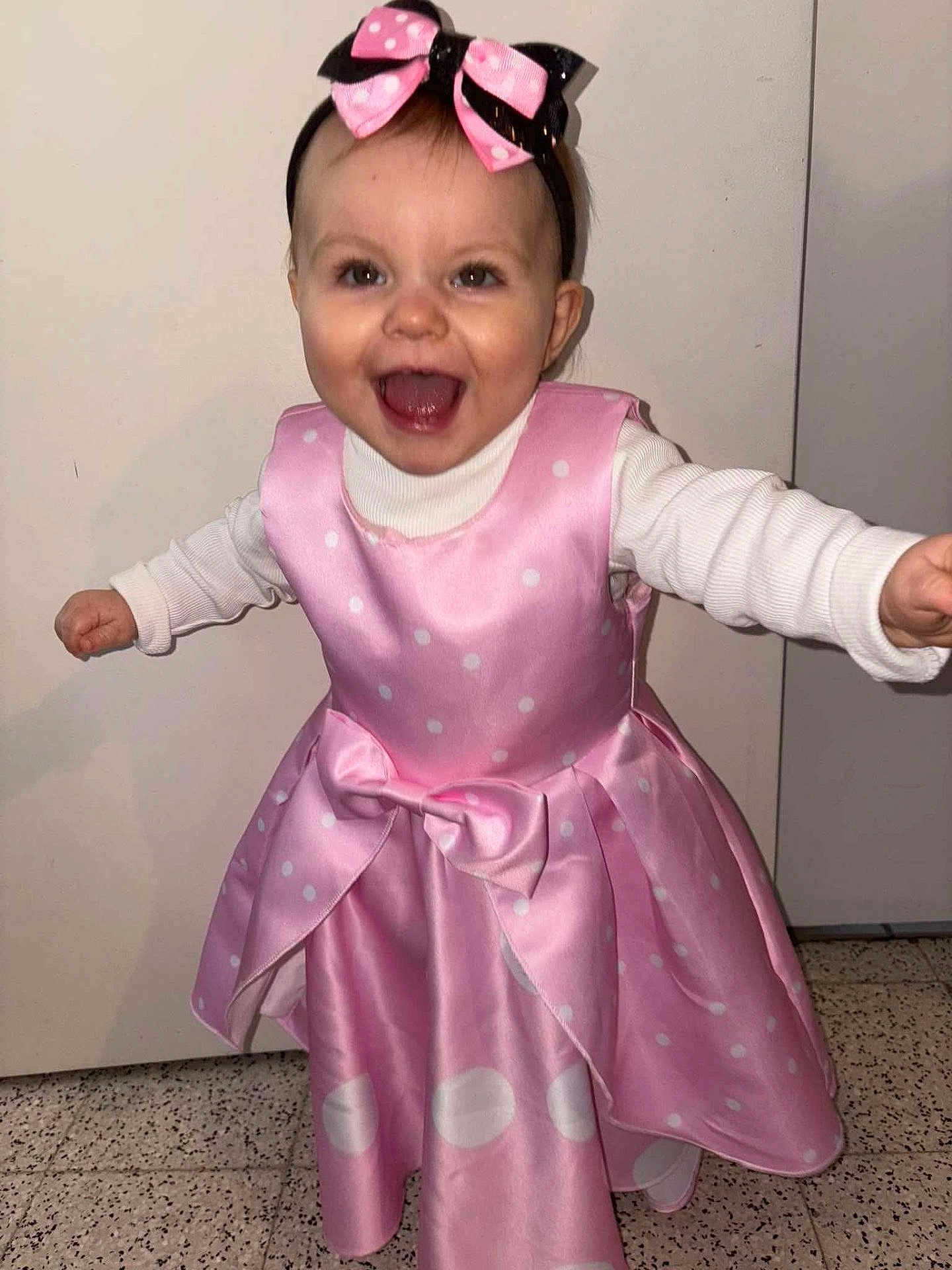 Noëlya participe au concours pour gagner de l'argent avec cette photo : toddler, child, pink_dress, bow, headband, smiling, happy, indoor, floor, polka_dot, white_shirt, long_sleeve, standing, person, face, hair, eyes, mouth_open, arms_outstretched, celebration