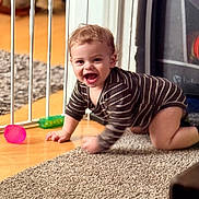 Luca joined the competition — help win amazing prizes! baby, crawling, striped_onesie, carpet, baby_gate, toy_ball, toy_block, indoor, floor, child, happy, smiling, person, young_child, home, wood_floor, play, cute, infant, furniture