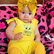 Kataleya-Valentina a rejoint le concours — aidez-le/la à gagner de superbes lots ! baby, child, yellow_clothing, headband, bow, sitting, cushion, pink_pattern, black_pattern, indoor, cute, portrait, infant, person, fashion, colorful, expression, eyes, hand, footwear