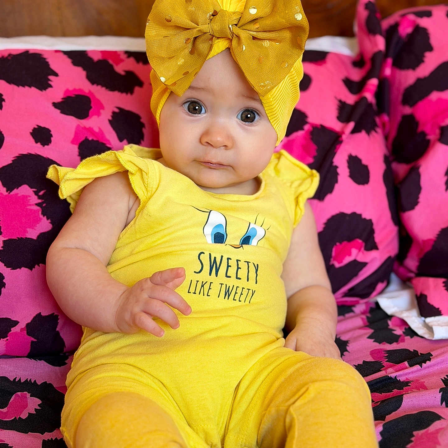 Kataleya-Valentina a rejoint le concours — aidez-le/la à gagner de superbes lots ! baby, child, yellow_clothing, headband, bow, sitting, cushion, pink_pattern, black_pattern, indoor, cute, portrait, infant, person, fashion, colorful, expression, eyes, hand, footwear