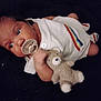 Izaiah is registered to the contest to win money with this photo: baby, child, close_up, colorful_stripes, comfort, cute, dark_background, face, hand, indoors, infant, knitted_clothing, lying_down, newborn, pacifier, portrait, sleepwear, soft_toy, teddy_bear, white_outfit