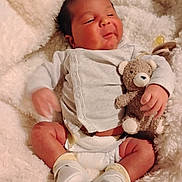 Izaiah is registered to the contest to win money with this photo: baby, infant, teddy_bear, blanket, soft_toy, white_booties, onesie, diaper, cute, smiling, cozy, fluffy, newborn, child, sleepy, hand, face, comfort, indoor, resting