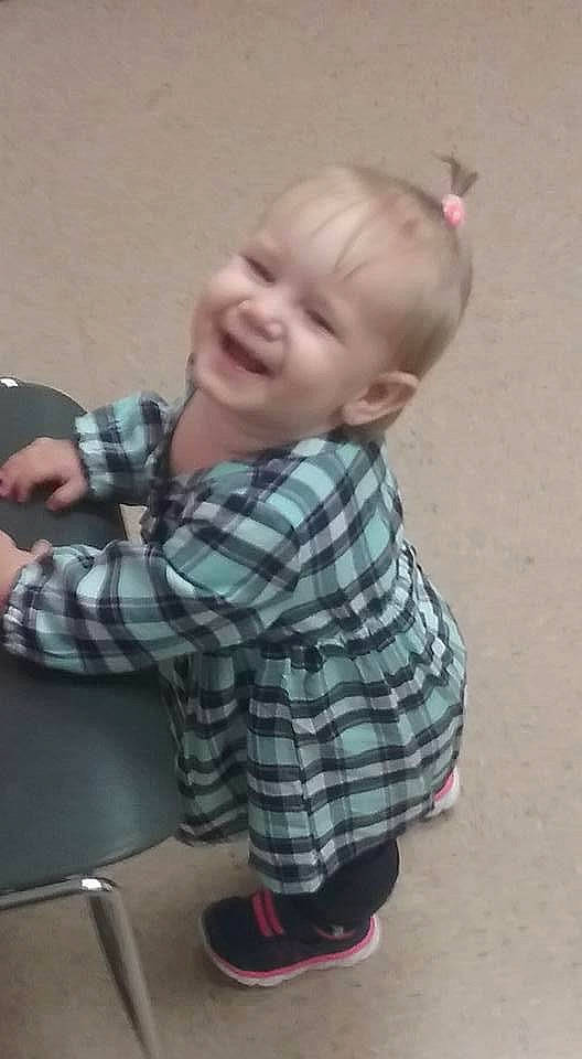 Emily is registered to the contest to win money with this photo: arm, baby, baby_toddler_clothing, cheek, elbow, eye, finger, flooring, hand, human_body, joy, pattern, person, plaid, sitting, sleeve, smile, standing, t_shirt, tartan