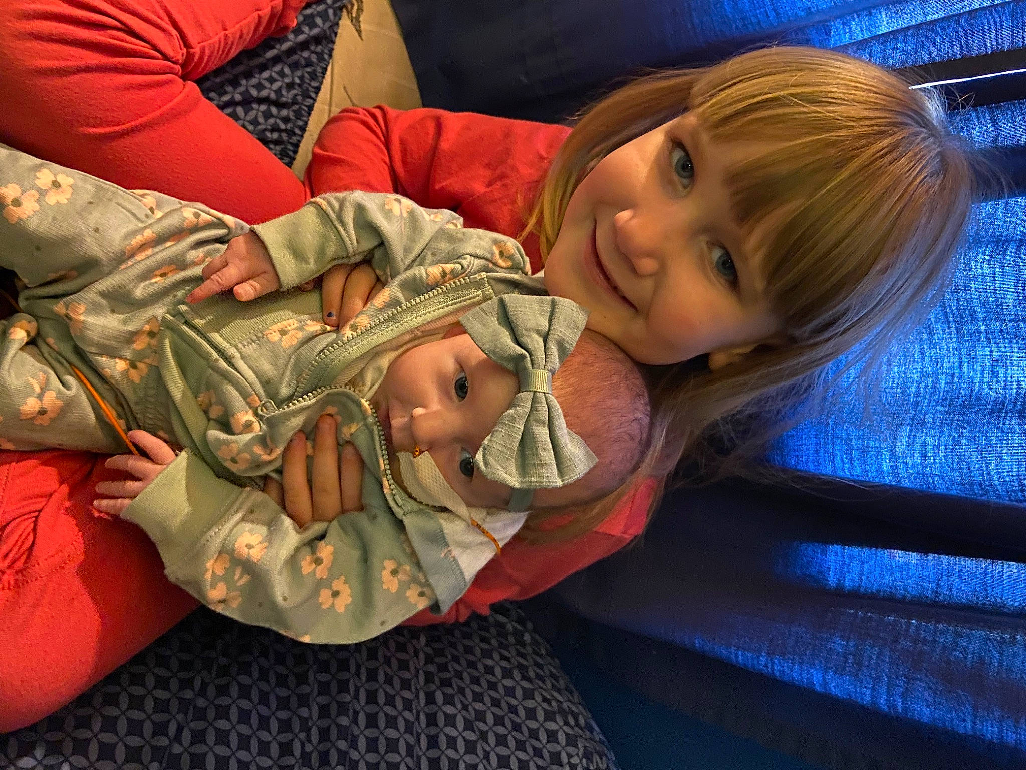 Kayla is registered to the contest to win money with this photo: abdomen, arm, brown_hair, child, comfort, couch, elbow, happy, head, human_leg, joy, lap, military_camouflage, mouth, pattern, person, sitting, smile, thigh, toddler