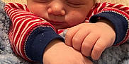 Mazen is registered to the contest to win money with this photo: baby, blanket, child, closeup, comfort, cozy, cute, face, hands, indoors, infant, newborn, peaceful, portrait, red_striped_clothing, relaxed, resting, sleeping, soft_texture, warm