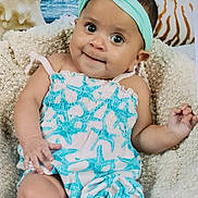 Jazmin is registered to the contest to win money with this photo: baby, infant, headband, romper, starfish_pattern, basket, knitted_blanket, seashell, background, portrait, cute, smiling, child, cozy, indoor, soft_texture, relaxed, person, closeup, happy