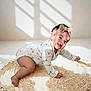 baby, infant, crawling, onesie, headband, bow, smiling, happy, cute, indoor, rug, woven_rug, natural_light, shadow, playful, child, person, floor, home, soft_light