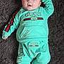 baby, infant, child, face, blue_eyes, smile, gucci_logo, branded_clothing, sweatshirt, sweatpants, socks, hand, fur_rug, carpet, lying_down, portrait, cute, indoors, soft_texture, human