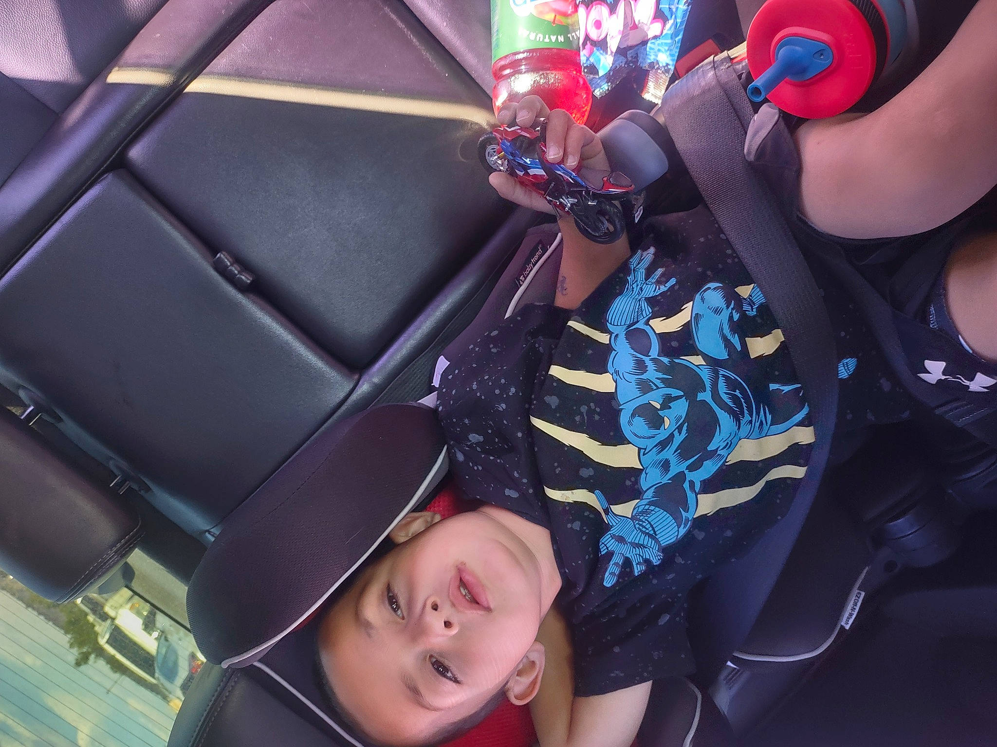 Finley is registered to the contest to win money with this photo: audio_equipment, auto_part, automotive_design, black_hair, blue, car_seat, clothing, cool, electric_blue, eyewear, finger, fun, gesture, leisure, mouth, person, snapshot, steering_wheel, t_shirt, toddler