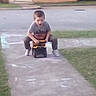 Paul is registered to the contest to win money with this photo: activity, boy, casual_clothing, chalk_drawings, child, concrete, daytime, fun, grass, house, lawn, outdoor, person, play, recreation, residential, sidewalk, toy_truck, transport, young