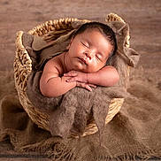 Jason is registered to the contest to win money with this photo: baby, sleeping, basket, brown, fabric, cozy, infant, peaceful, soft, hands, rest, wooden_floor, cute, portrait, newborn, child, wrapped, relaxed, indoors, warm_lighting