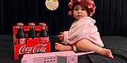 Sofia joined the competition — help win amazing prizes! baby, pink_robe, hair_curlers, vintage_phone, coca_cola, glass_bottles, black_background, sign, 10_month, child, curious, sitting, toy, retro, portrait, indoors, cute, wide_eyes, floor, hat