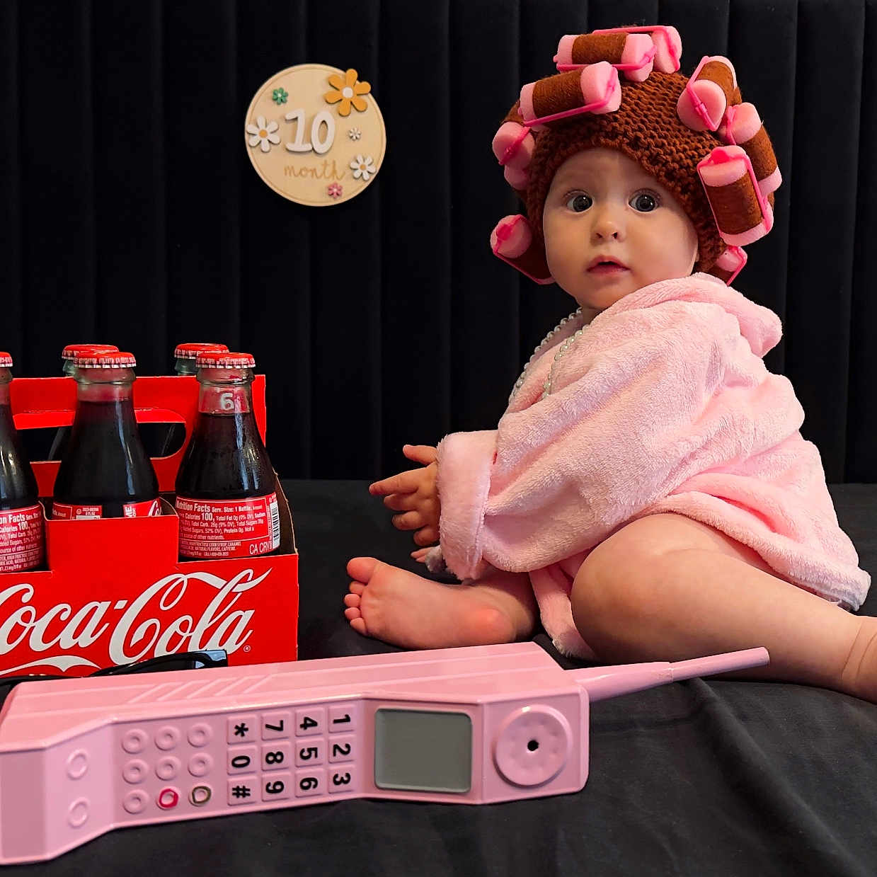 Sofia joined the competition — help win amazing prizes! 10_month, baby, black_background, child, coca_cola, curious, cute, floor, glass_bottles, hair_curlers, hat, indoors, pink_robe, portrait, retro, sign, sitting, toy, vintage_phone, wide_eyes