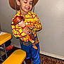 bench, blue_pants, boots, child, costume_party, cowboy_costume, flash_photo, hands, happy, hat, indoor, playing, portrait, rug, smiling, snack_bag, toy, wall, woody_doll, yellow_shirt