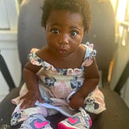 Jahmira is registered to the contest to win money with this photo: toddler, child, sitting, dress, shoes, sneakers, pink, gray, curly_hair, indoor, chair, cute, portrait, young_child, person, fashion, footwear, expression, looking_at_camera, pout