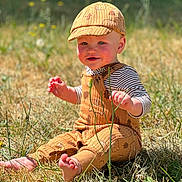 Everest joined the competition — help win amazing prizes! toddler, child, outdoor, grass, sunlight, hat, cap, barefoot, smiling, cute, nature, baby, sitting, clothing, striped_shirt, yellow, greenery, portrait, daylight, playful