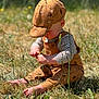 Everest is registered to the contest to win money with this photo: toddler, child, baby, grass, outdoor, barefoot, cap, overalls, striped_shirt, flower, nature, sunlight, summer, playing, sitting, cute, young_child, daytime, field, casual_clothing