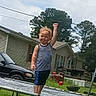 toddler, child, trampoline, backyard, grass, house, car, trees, sky, outdoor, fence, clothing, tank_top, shorts, raised_fist, standing, daytime, play, expression, fun
