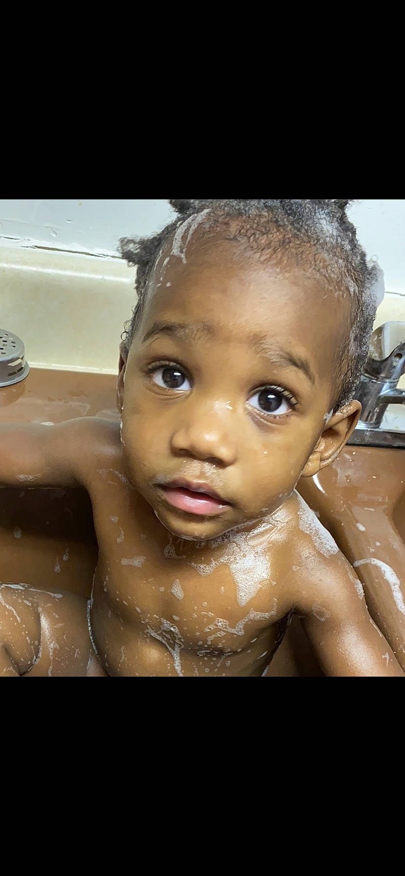 Santana is registered to the contest to win money with this photo: baby_bathing, bathing, black_hair, cheek, child, close_up, eyebrow, face, forehead, hair, hairstyle, head, human, lip, nose, person, skin, smile, washing, water
