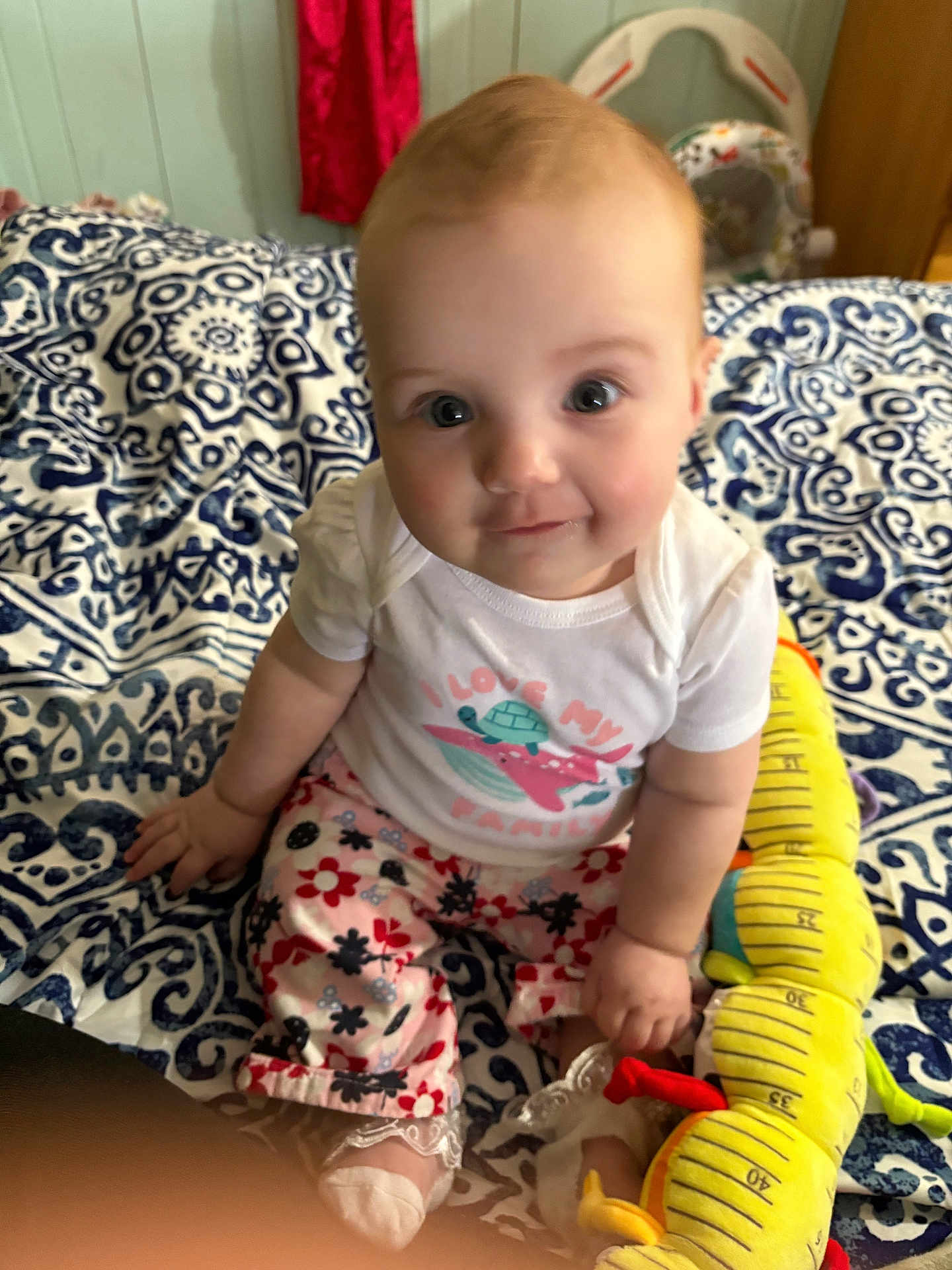 Milah joined the competition — help win amazing prizes! baby, child, infant, sitting, toy, blanket, pattern, clothing, cute, indoor, face, smile, colorful, person, blue, white, red, yellow, decor, play