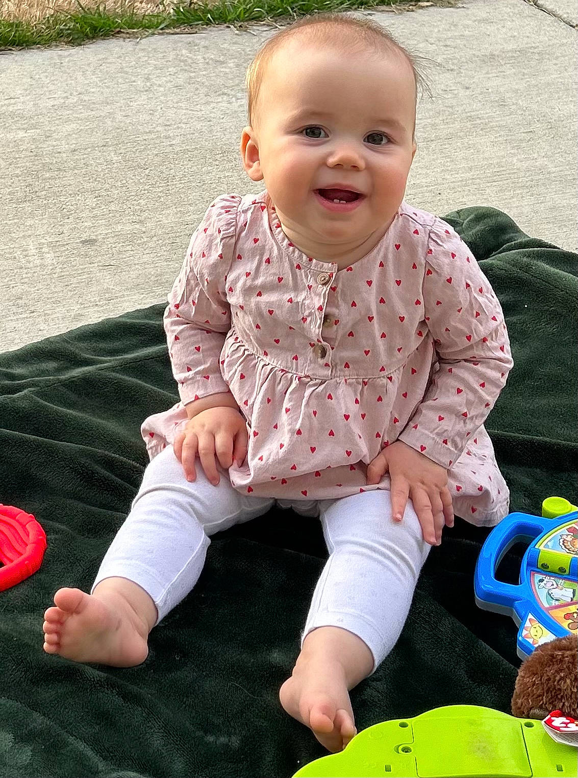 Cassandra is registered to the contest to win money with this photo: baby, baby_playing_with_toys, baby_toddler_clothing, cheek, child, face, fun, grass, happy, joy, leg, leisure, pattern, people_in_nature, person, play, sitting, skin, sleeve, smile