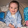 Eli is registered to the contest to win money with this photo: baby, child, smiling, blue_robe, blanket, plush_toy, indoor, happy, cute, face, person, sitting, soft_toys, cozy, infant, portrait, warm, comfort, home, toddler
