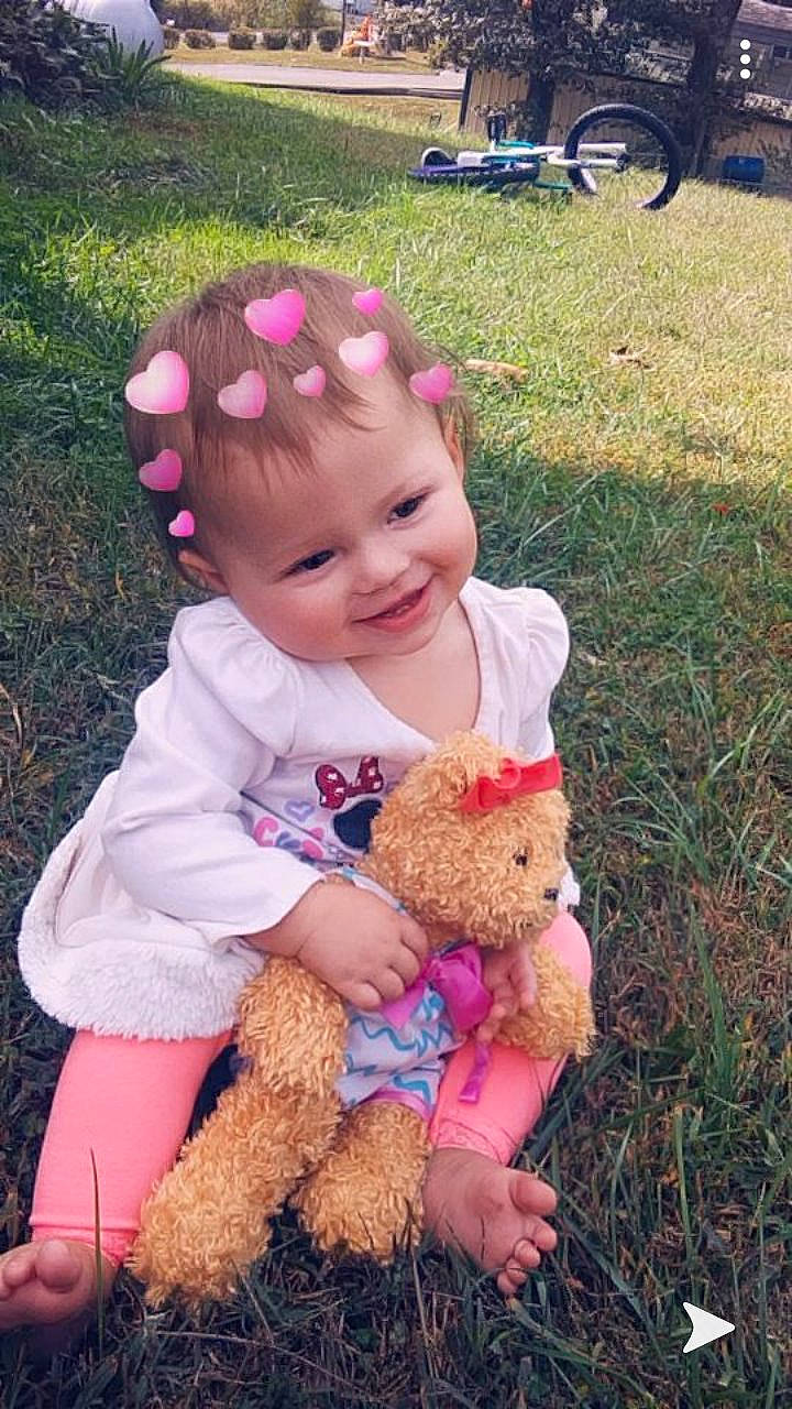 Arabella is registered to the contest to win money with this photo: baby, child, grass, headgear, interaction, joy, person, pink, play, smile, stuffed_toy, teddy_bear, toddler, toy