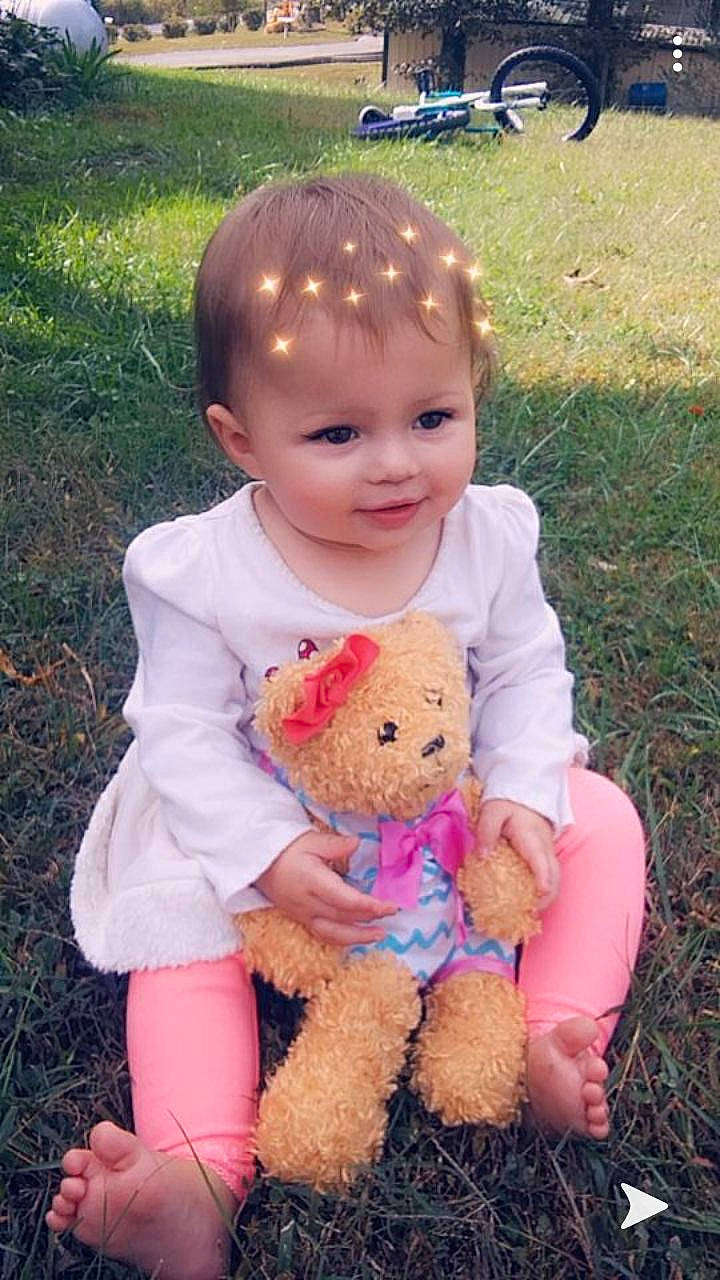 Arabella is registered to the contest to win money with this photo: baby, baby_toddler_clothing, cheek, child, grass, person, pink, play, sitting, skin, smile, stuffed_toy, teddy_bear, toddler, toy