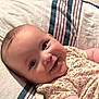 baby, smiling, infant, towel, striped_towel, floral_outfit, cute, lying_down, happy, face, skin, child, indoors, person, young_child, cheeks, eyes, clothing, soft_texture, comfort