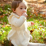 Stormi is registered to the contest to win money with this photo: bodypart, child, clothing, eating, face, female, finger, food, girl, grass, hand, head, knitwear, leaf, person, photography, plant, portrait, sitting, sweater