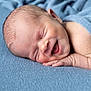 baby, newborn, sleeping, smiling, blue_blanket, infant, face, hand, skin, peaceful, closeup, portrait, soft_texture, cozy, cute, child, resting, happy, indoors, toddler