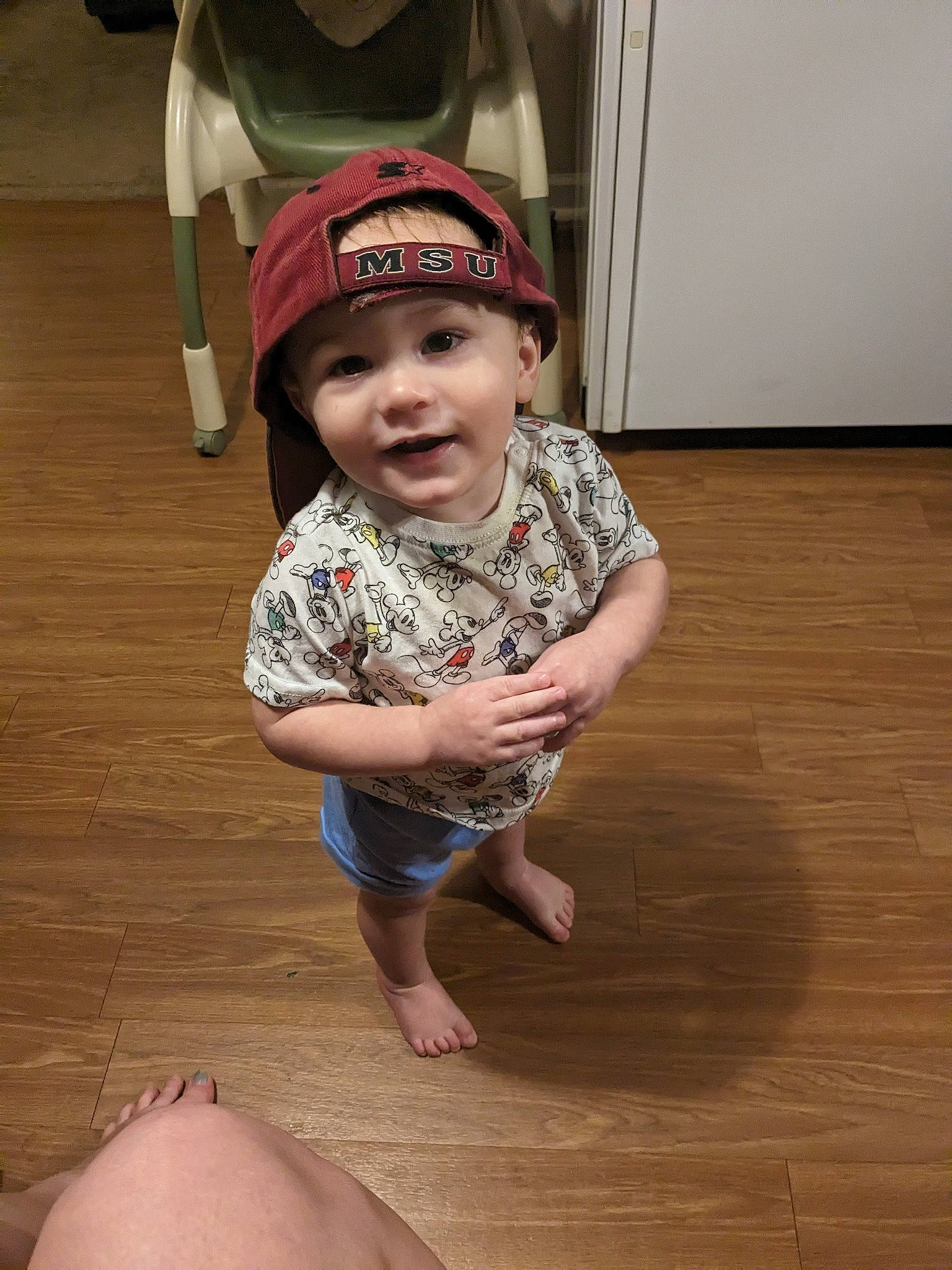 Desmond is registered to the contest to win money with this photo: baby, baby_toddler_clothing, barefoot, baseball_cap, cap, child, eye, facial_expression, floor, flooring, foot, fun, happy, hardwood, headwear, pattern, person, skin, sleeve, smile