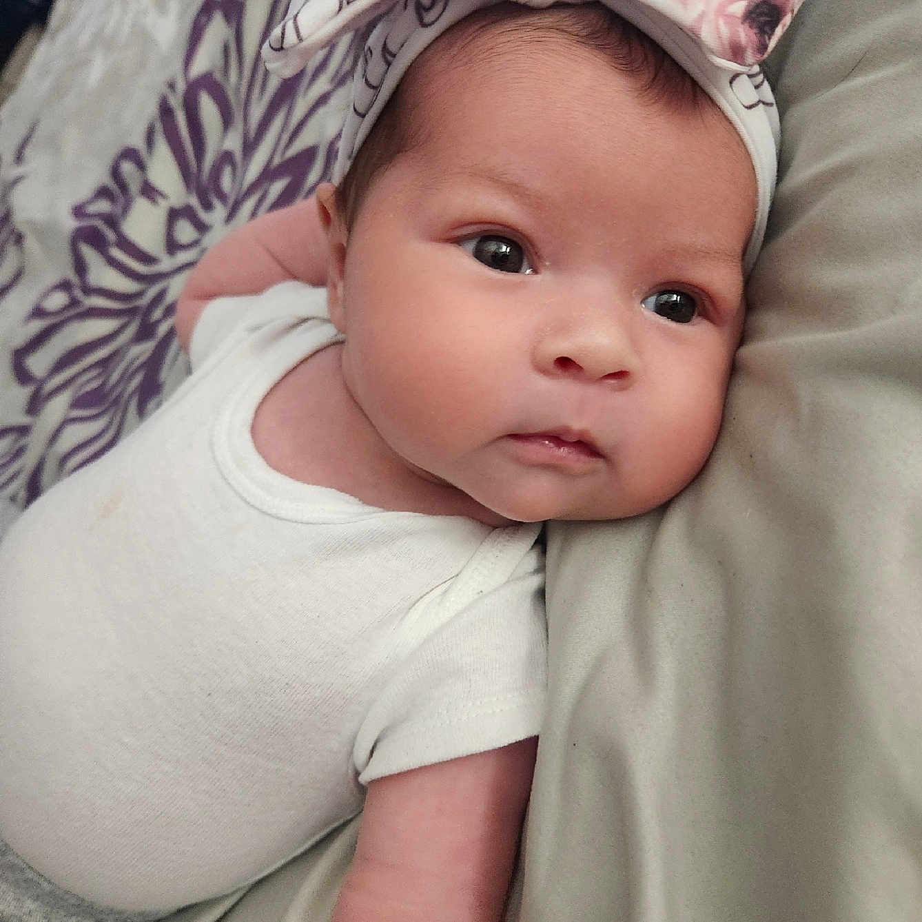 Lily joined the competition — help win amazing prizes! baby, infant, headband, bow, white_clothing, lying_down, bed, blanket, soft_fabric, face, cute, child, portrait, skin, eyes, arm, baby_girl, close_up, indoors, comfortable