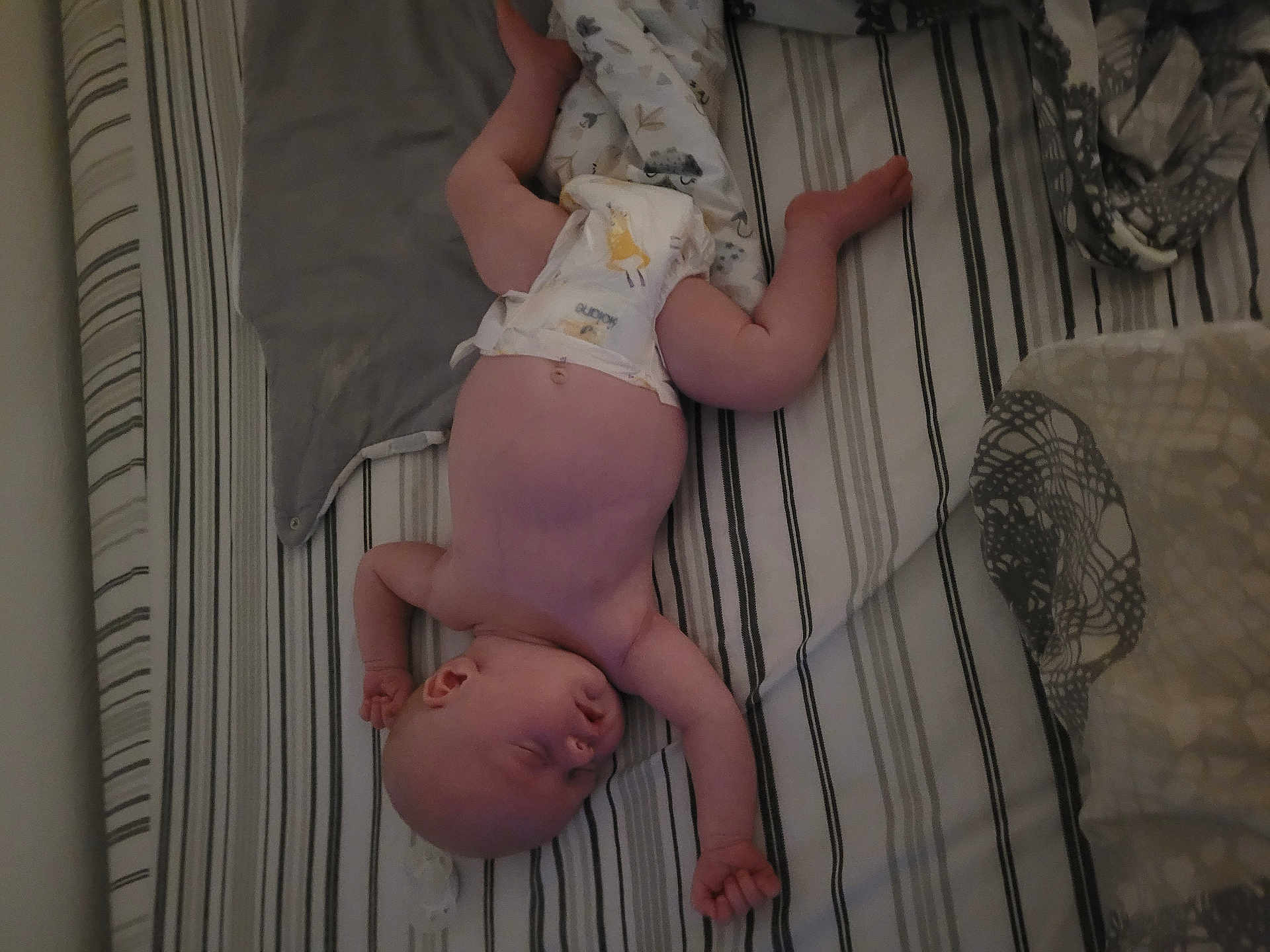 Anna participe au concours pour gagner de l'argent avec cette photo : baby, sleeping, bed, blanket, diaper, striped_bedspread, infant, skin, arm, leg, head, peaceful, cozy, rest, indoors, person, newborn, soft, comfort, nap