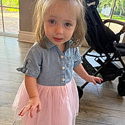 Emma Rose is registered to the contest to win money with this photo: toddler, child, girl, indoor, dress, pink_skirt, denim_shirt, bow, curly_hair, stroller, window, floor, light, innocent, cute, portrait, smiling, person, young, casual