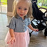 toddler, child, girl, indoor, dress, pink_skirt, denim_shirt, bow, curly_hair, stroller, window, floor, light, innocent, cute, portrait, smiling, person, young, casual