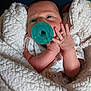 baby, newborn, pacifier, blanket, blue_pillow, infant, wrapped, cute, sleepy, soft_texture, hand, face, clothing, indoors, resting, cozy, child, person, portrait, comfort