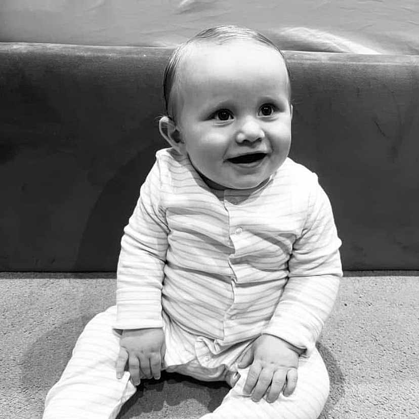 Teddy joined the competition — help win amazing prizes! baby, black_and_white, carpet, child, couch, cute, face, furniture, happy, home, indoor, infant, monochrome, pajamas, person, portrait, sitting, smiling, striped_clothing, young_child