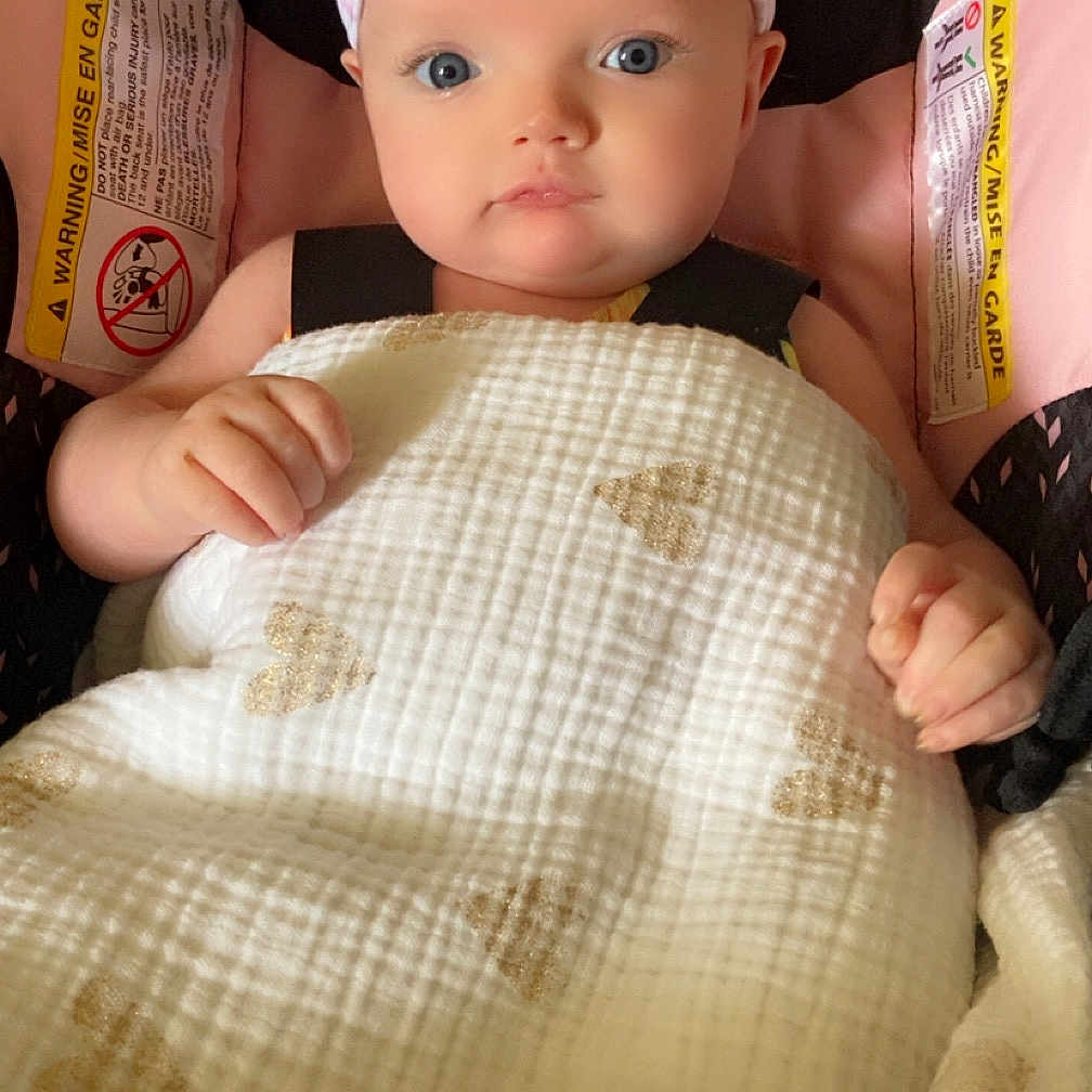 Scarlett joined the competition — help win amazing prizes! adorable, baby, blanket, blue_eyes, car_seat, child, closeup, clothing, cute, headband, heart_pattern, indoors, infant, person, portrait, safety_warning, sitting, soft_texture, wrapped, young_child