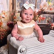 Evie is registered to the contest to win money with this photo: baby, child, smiling, dress, headband, bow, radiator, vintage, flower, floral, background, indoor, portrait, cute, chubby, blue_eyes, skin, hands, window, decor